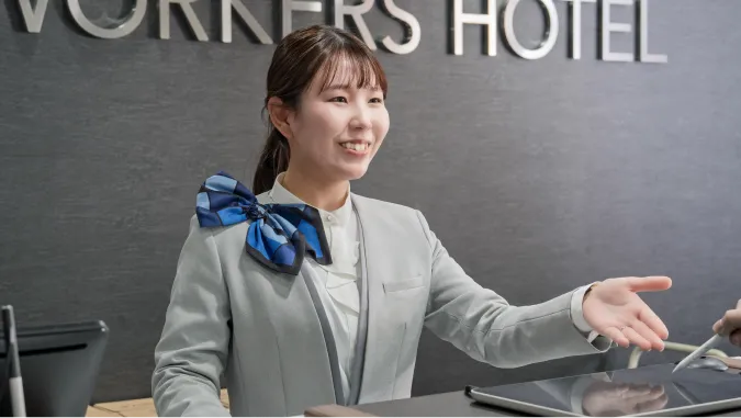 フロントで笑顔で挨拶をするホテルの女性スタッフ