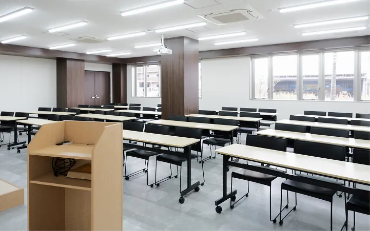 スクール形式で整然とデスクと椅子が並べられた、明るく広々とした会議室。正面にはホワイトボードが設置されており、セミナーや研修にそのまま活用できる機能的な空間。